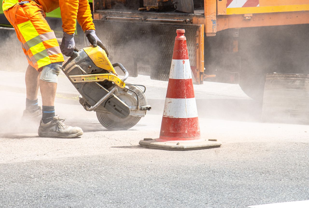Mastering the First Impression: Your intriguing post title goes here A construction worker cutting asphalt with a large saw next to a traffic cone on a street.